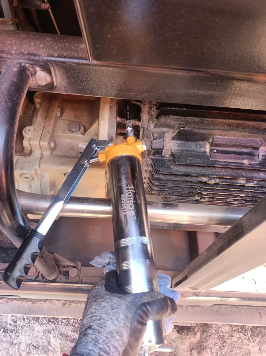 Técnico lubricando rodamientos de motor con engrasadora
